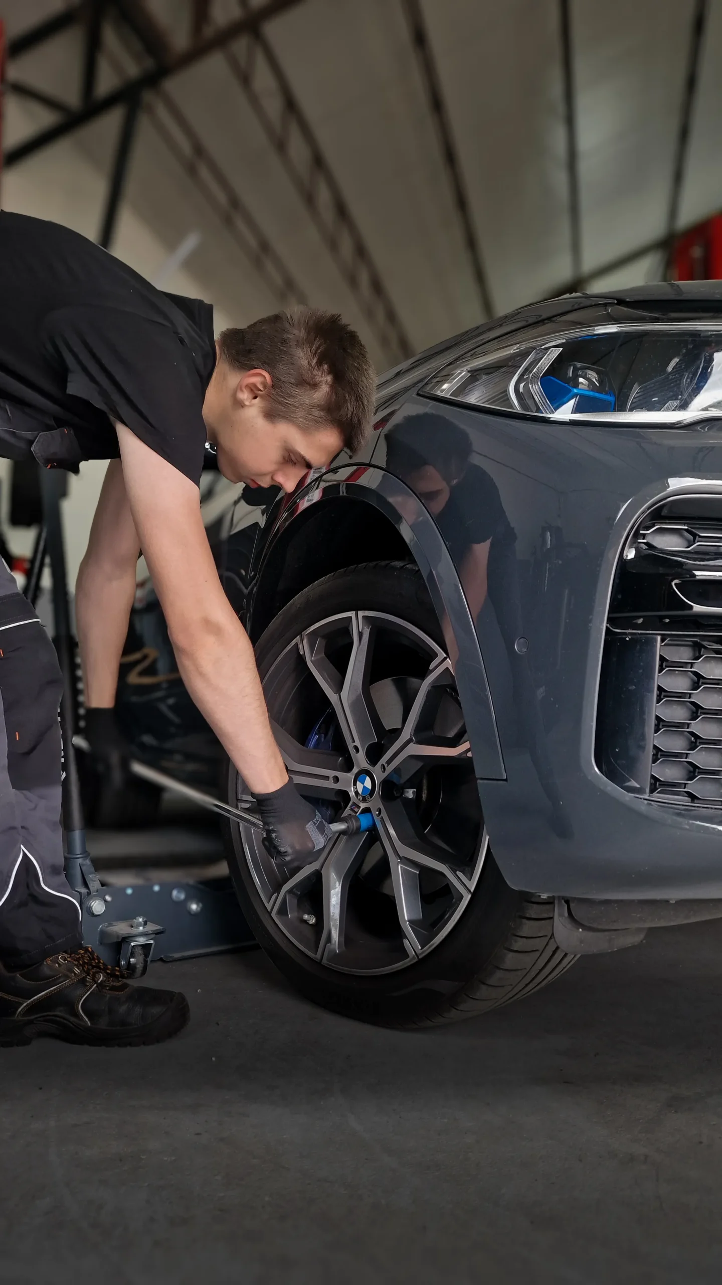 Person using a wrench to remove a car’s front wheel