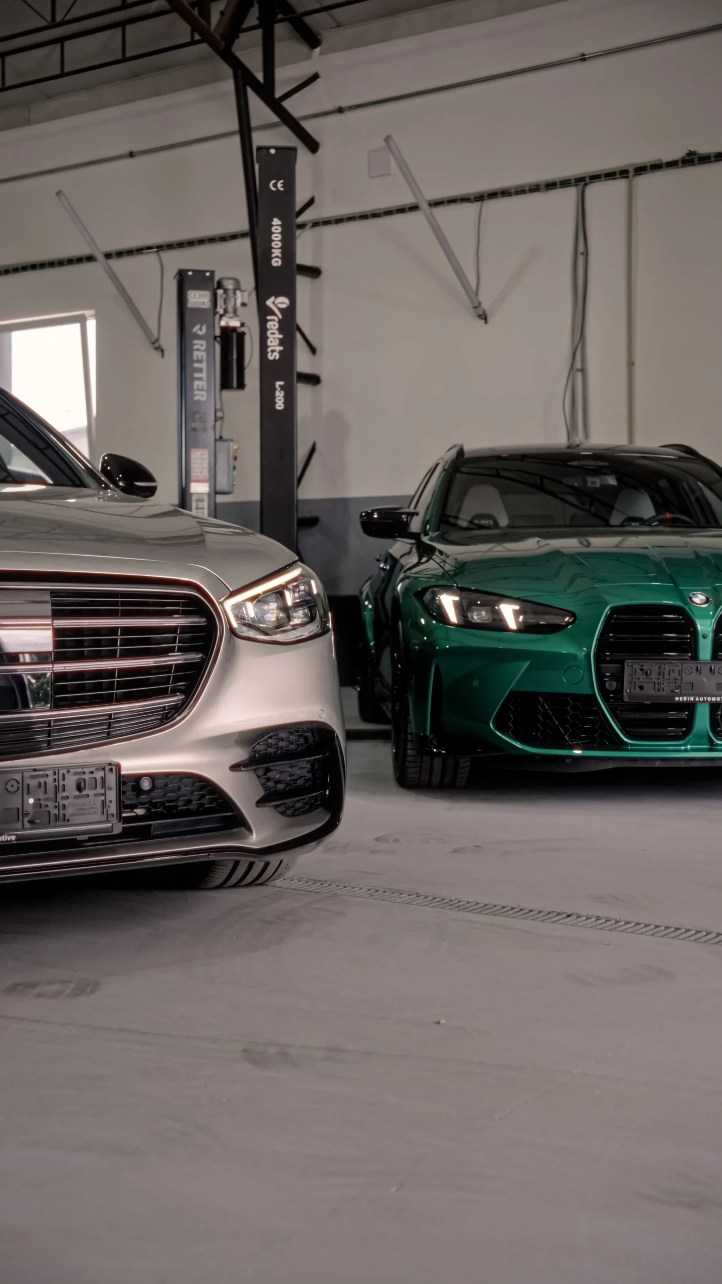 Silver and green cars beside workshop lifts