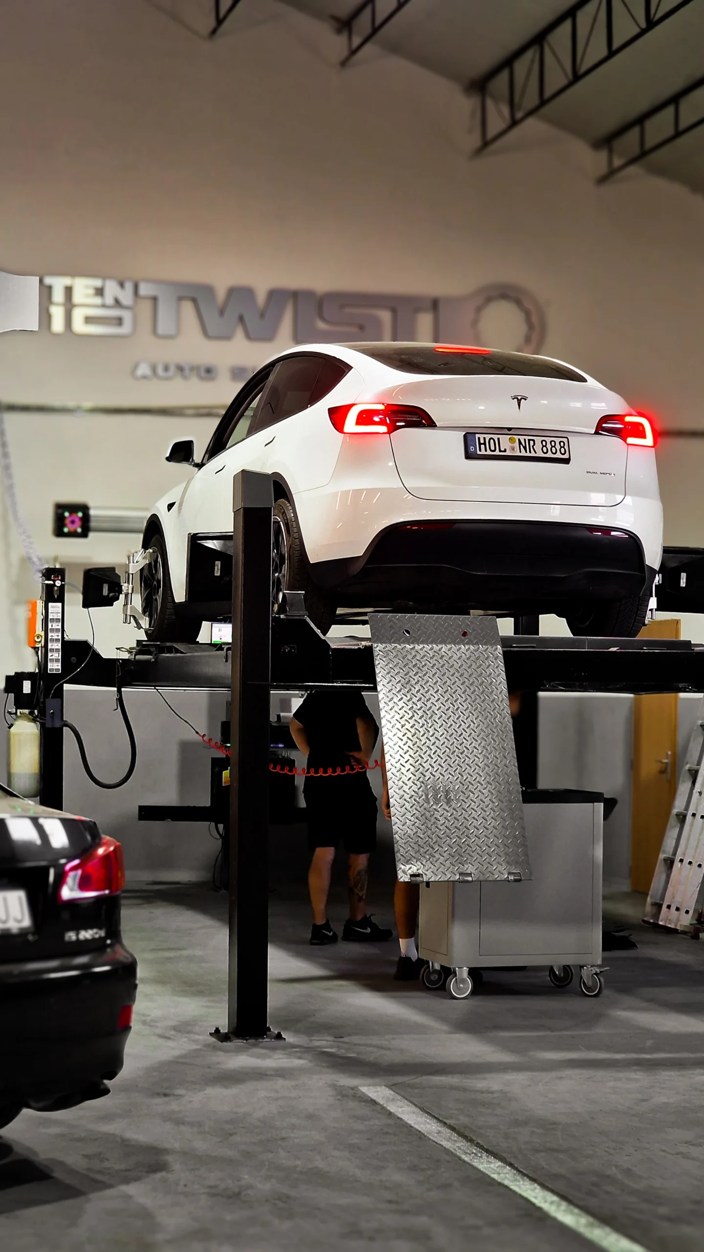 White car on a lift with wheel alignment equipment