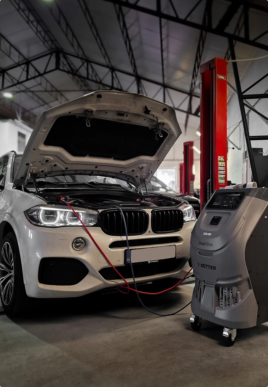 Car with its bonnet open, connected to an air conditioning service machine